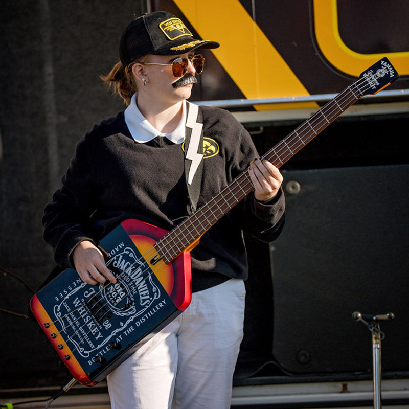 Michelle Van Hayden holding a Jack Daniel's branded bass guitar in front of the Vanbulance