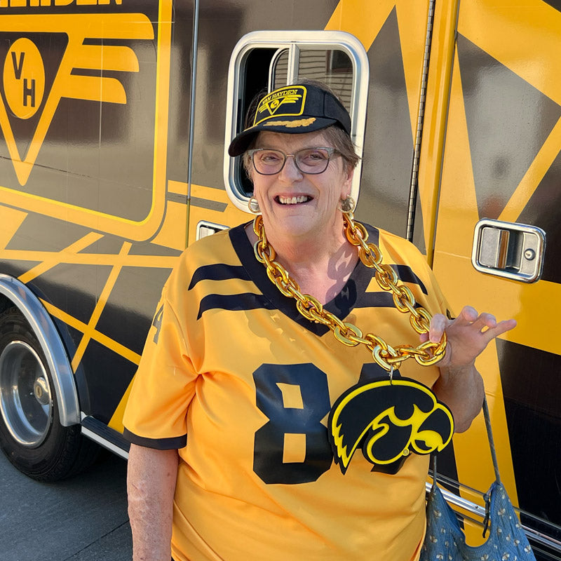Oma Van Hayden wearing a yellow Iowa football jersey with a large chain necklace with the tiger hawk logo in front of the Vanbulance