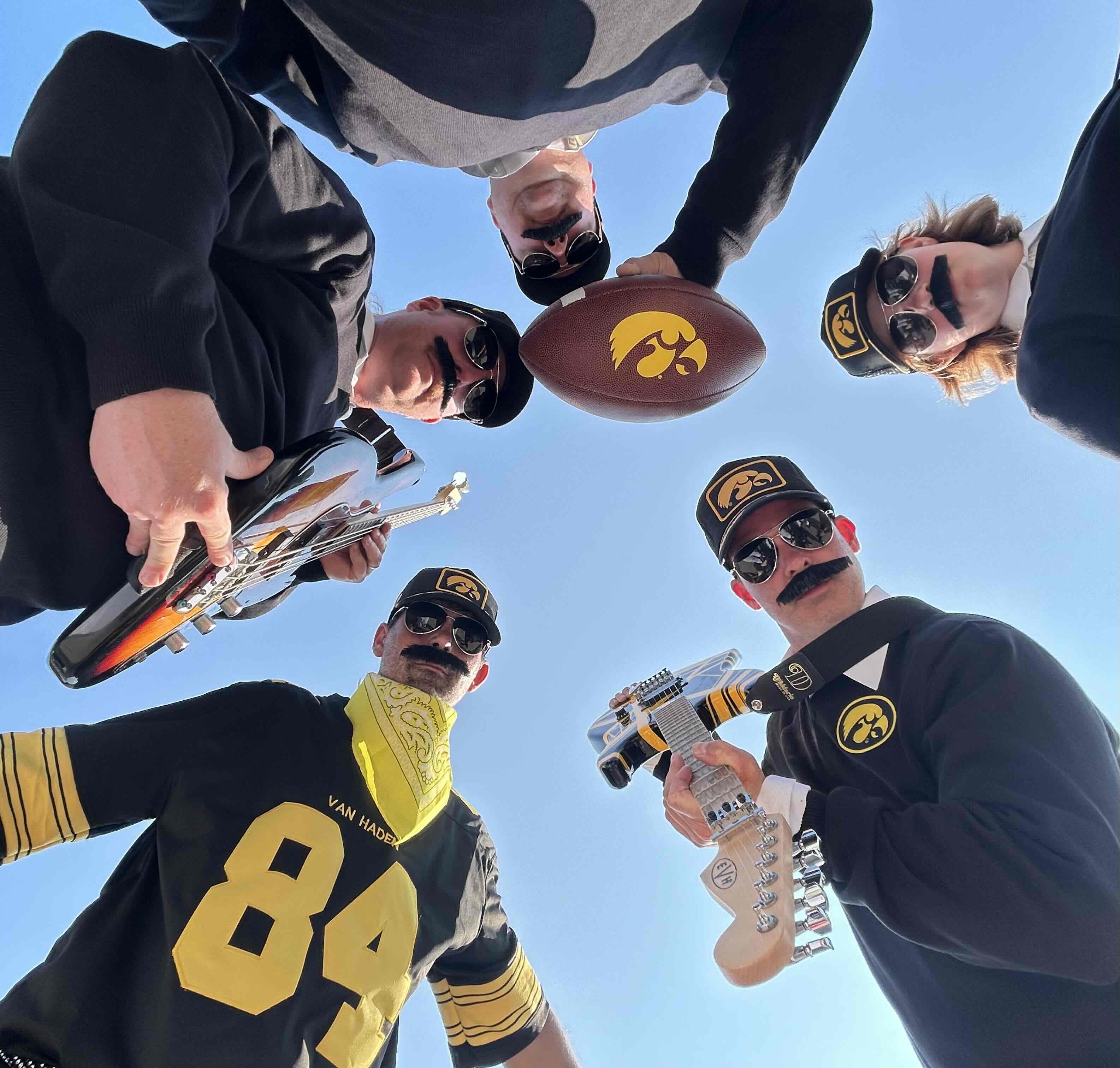 Van Hayden Band holding instruments holding an Iowa Hawkeye football